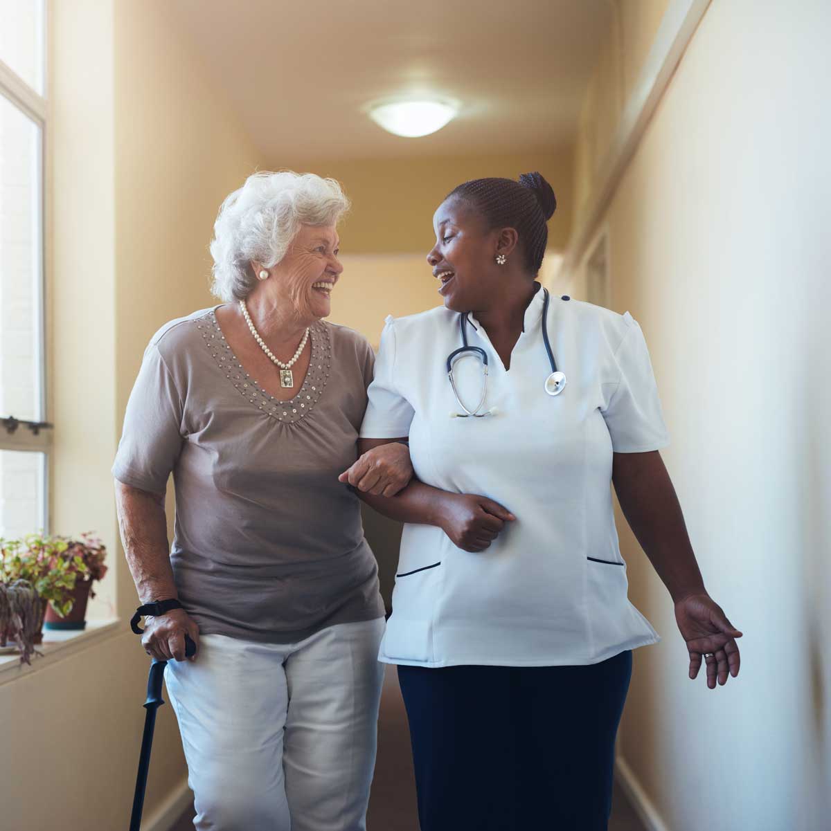 Smiling healthcare worker and senior woman walking together