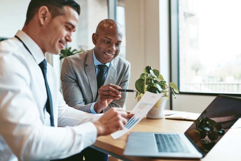 Two diverse businessmen going over graphs together in an office