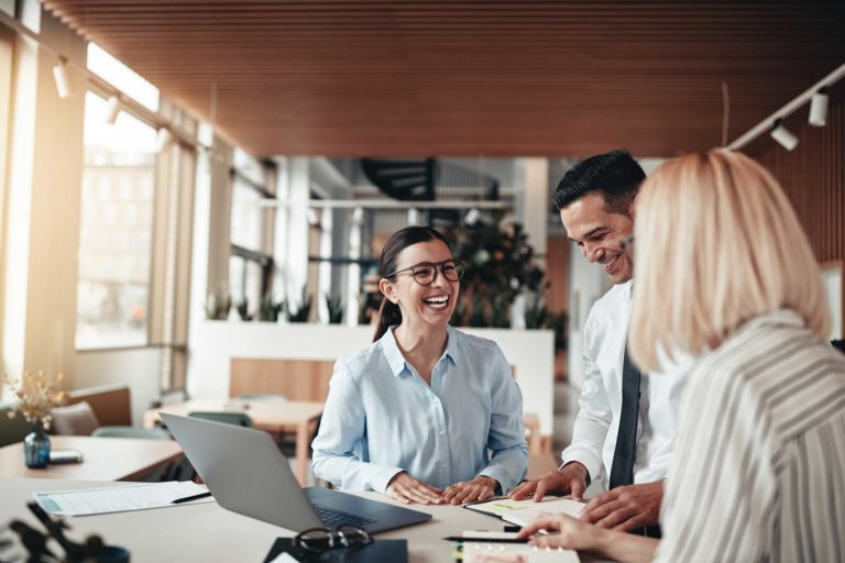 Businesspeople laughing while working at an office table