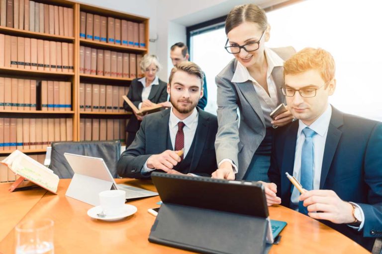 Lawyers in their law firm working on computer with books in background